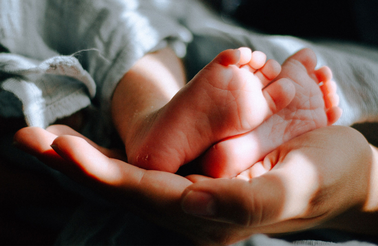 Baby's feet held by mother in dark room